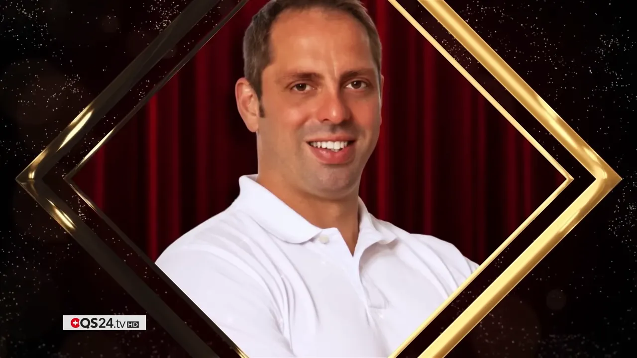 QS24 AWARD 2025: Versöhnung in der Medizin — Preisträgerinnen und Preisträger 8 Porträt eines Mannes in weissem Poloshirt vor rotem Vorhang, eingerahmt von goldener Grafik