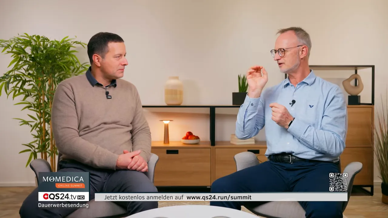 Zwei Experten im Studio, einer erklärt mit deutlicher Handgestik die Zusammenhänge der Heilungsebenen.