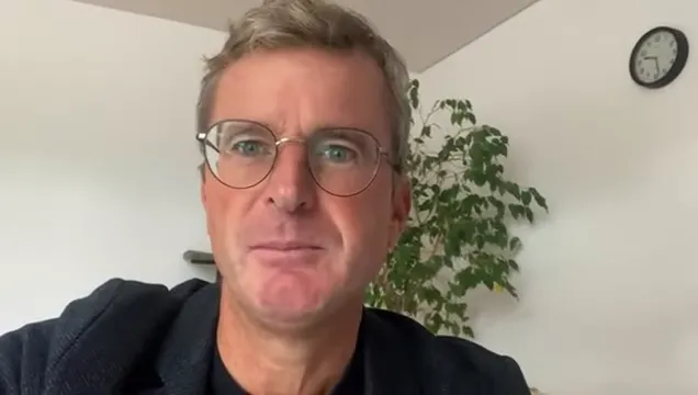 klare Nahaufnahme einer Person mit offenem Blick, Innenraum mit Pflanze und Uhr