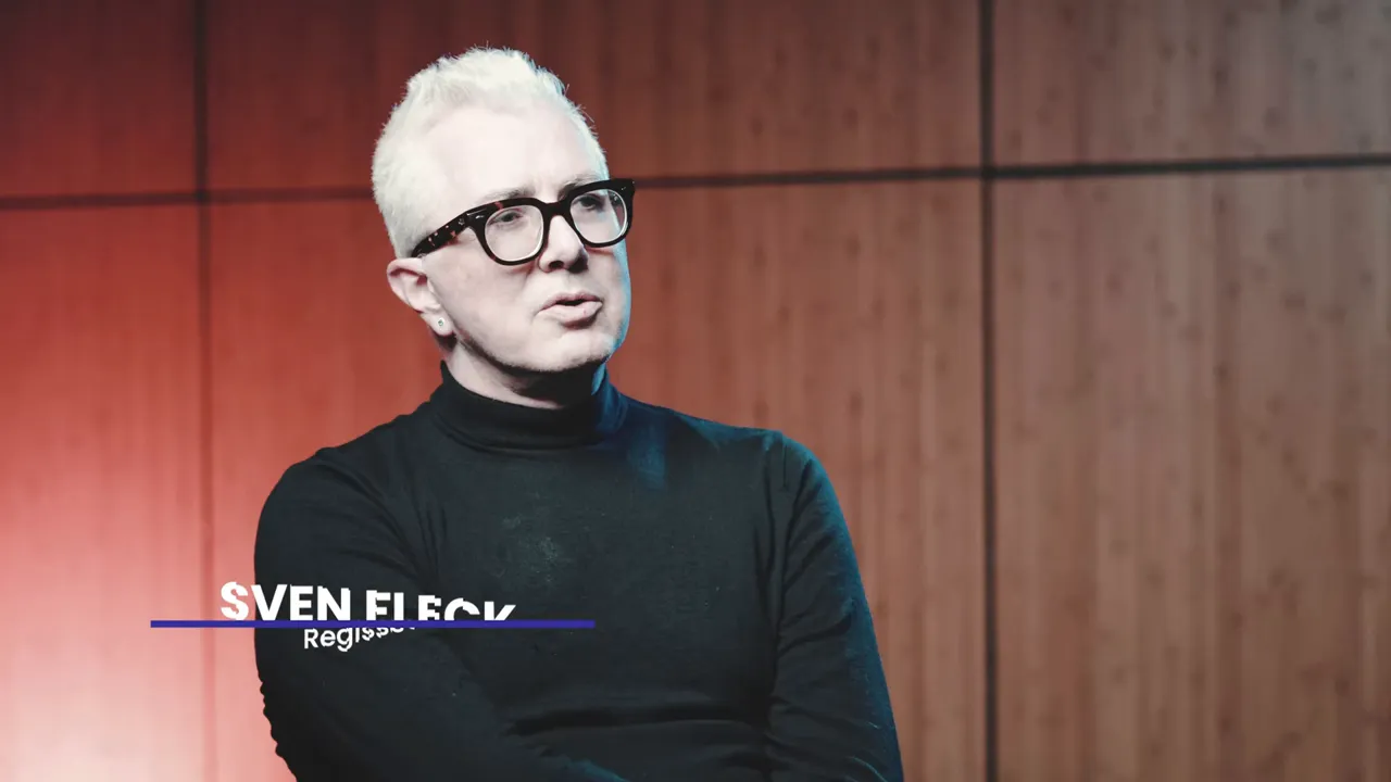 Person im Studio-Interview vor holzvertäfelter Wand