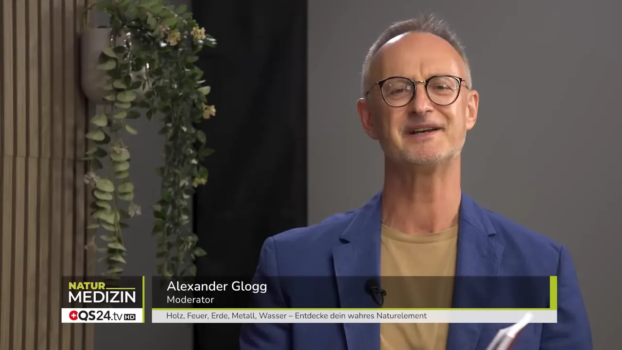 Nahaufnahme des Moderators im Studio, lächelnd mit sichtbarer Titelleiste unten.