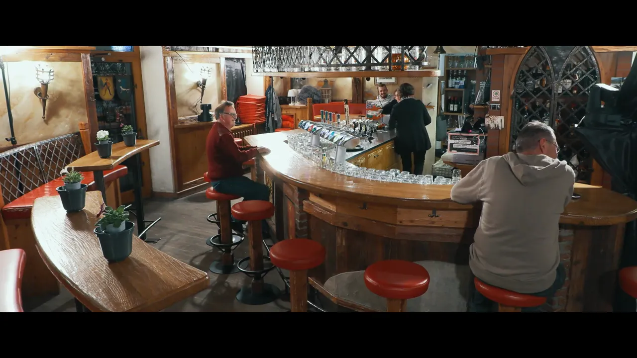 Weitwinkelaufnahme der Bar im Bäji-Pub mit Gästen, Wirtin und Zapfanlage