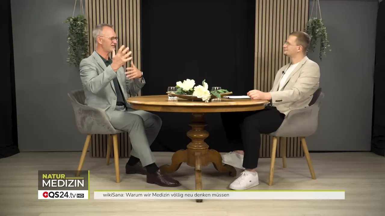 Warum wir Medizin völlig neu denken müssen - Das Interview mit Alexander Glogg, Gründer von wikiSana und QS24, Brückenbauer zwischen Schulmedizin und Ganzheitsmedizin 3 Weitwinkelaufnahme zweier Personen beim Interview, der Gast gestikuliert zur Verstärkung einer Erklärung