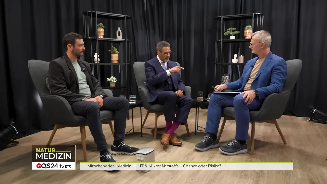 Weitwinkelaufnahme von drei Personen im Studio; der mittlere Experte zeigt mit der Hand auf, während er das IHHT‑Protokoll erklärt.