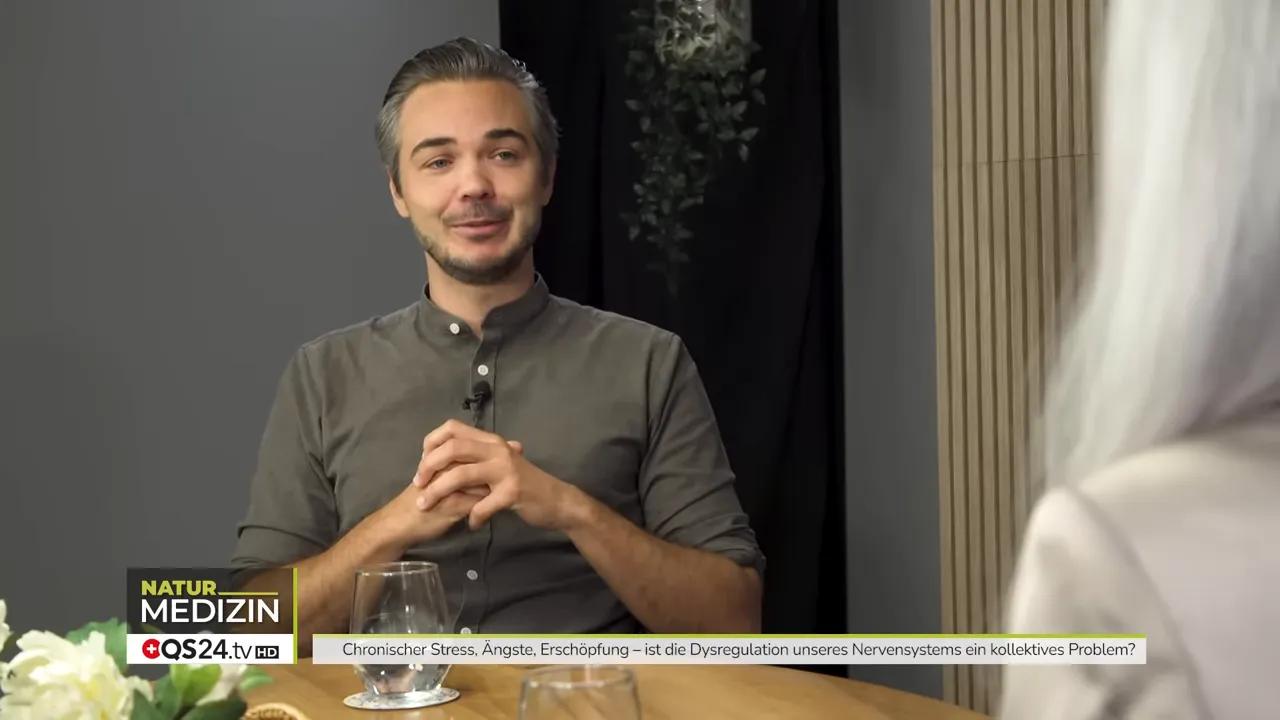 Stress, Nervensystem und Prävention - Interview mit Timo Janisch, Epigenetik‑Coach und TraumaDialog Practitioner 1 Timo Janisch lächelnd und überlegt, Hände zusammengelegt, Interview-Porträt