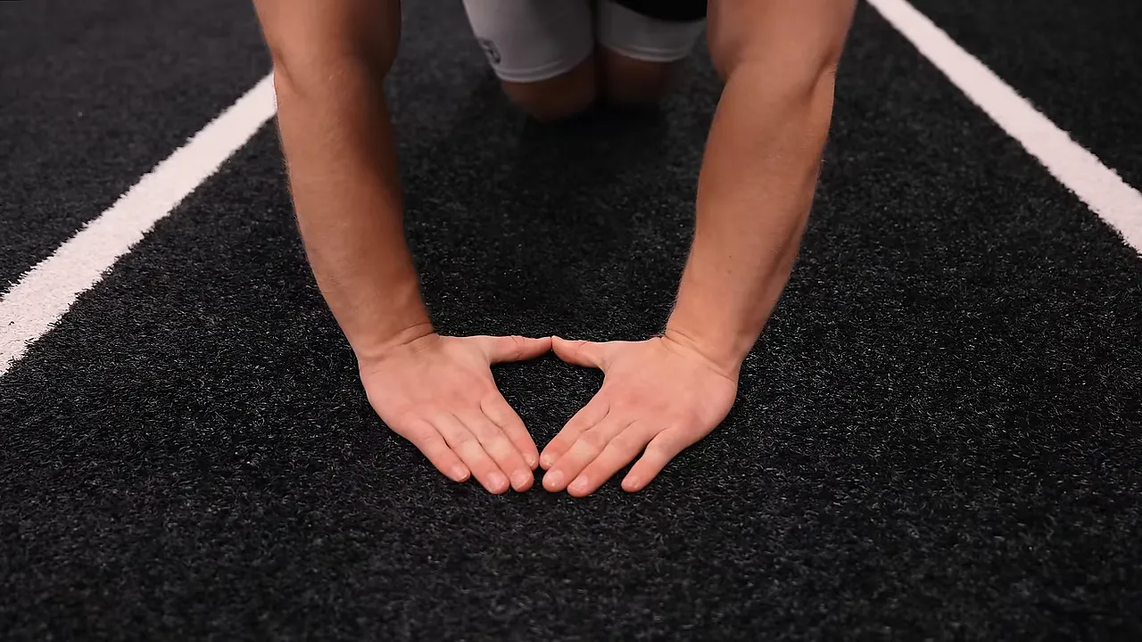 Close-up of hands on the floor with thumbs and index fingers forming a diamond