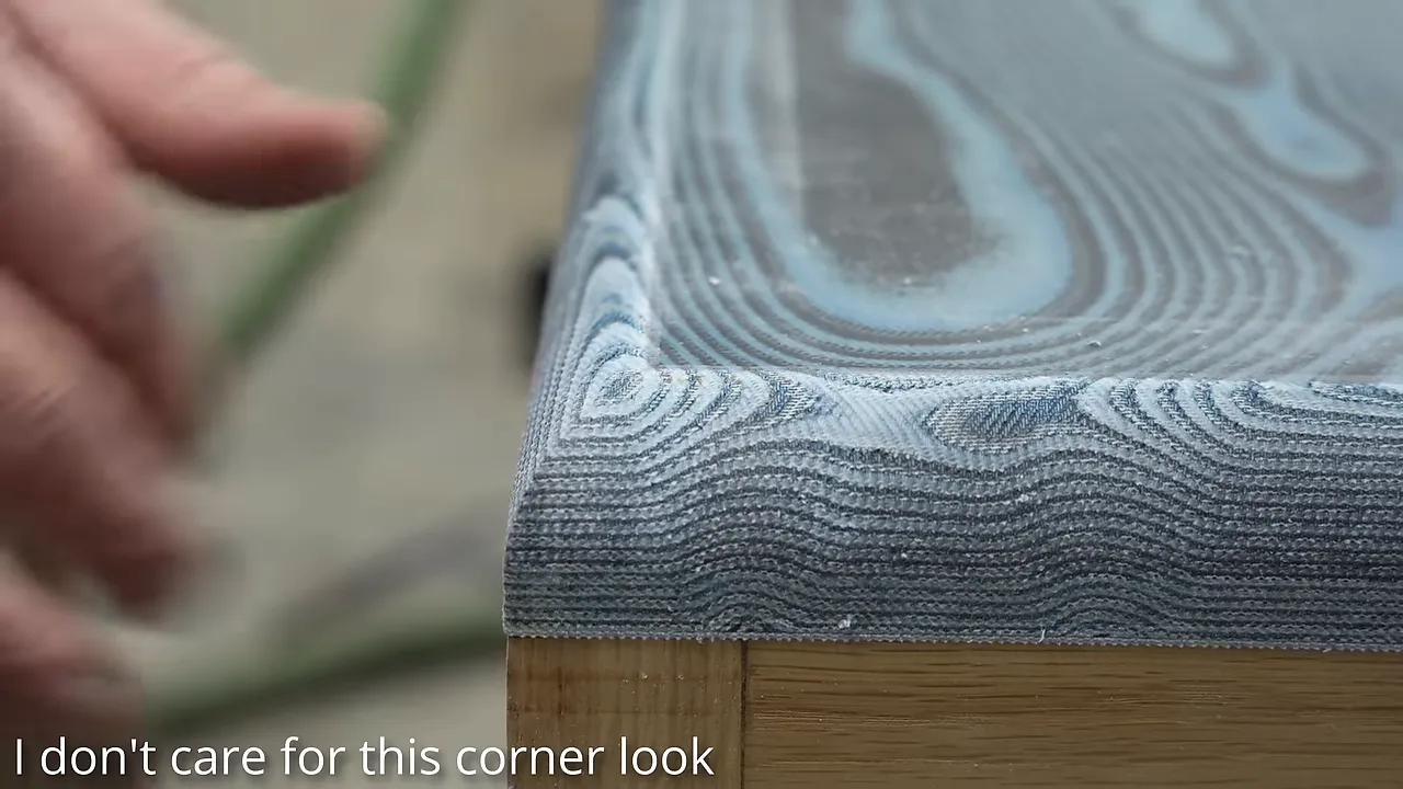 Close-up of a rounded denim tabletop corner with fine alternating layers above a white oak base
