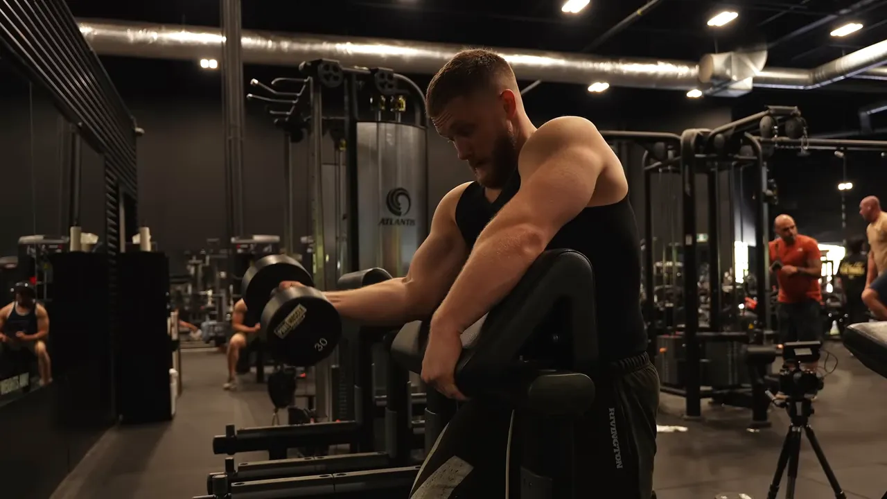 Dumbbell preacher curl with the upper arm supported on an angled pad near the bottom position