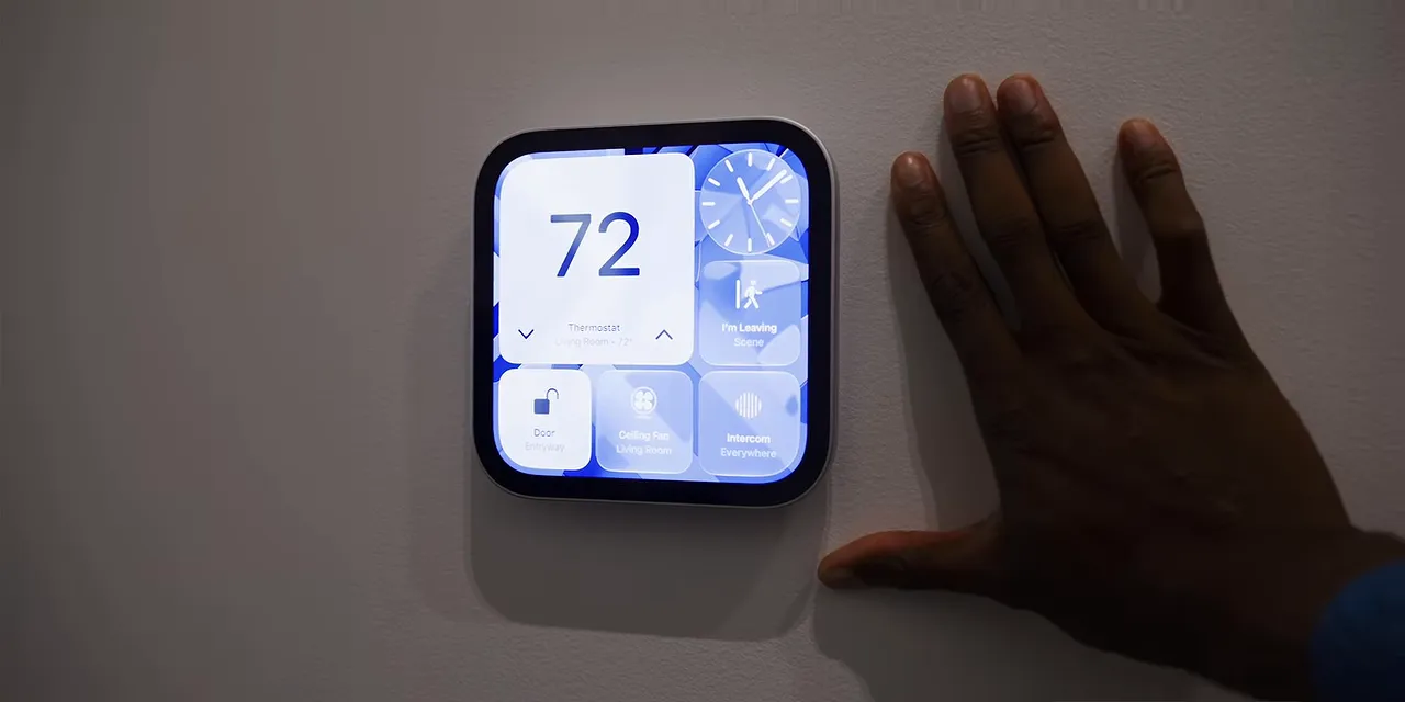 Wall-mounted HomeView displaying a weather dashboard with a hand beside it for scale