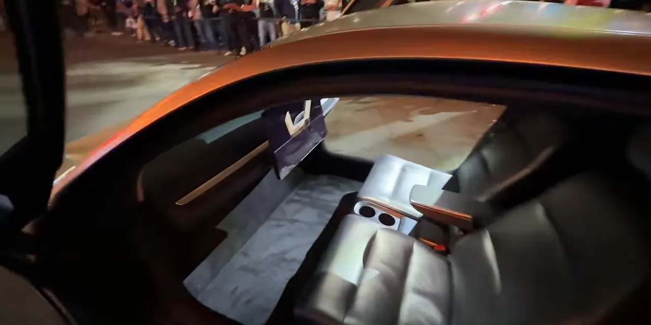 Cybercab cabin with two seats, a central screen, and no steering wheel