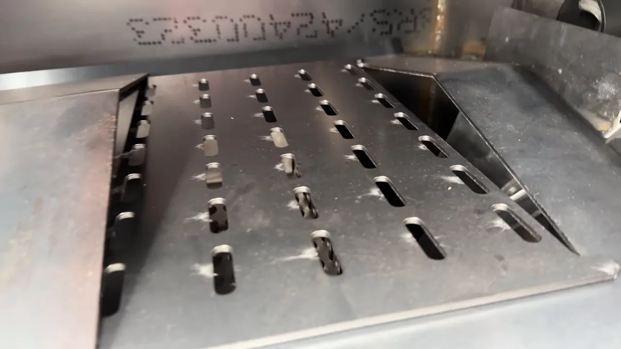 Steel deflector plate slid aside to expose a slotted section above the pellet fire area