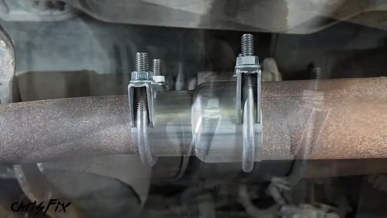 Exhaust reducing coupler installed between two pipes with a clamp at each end