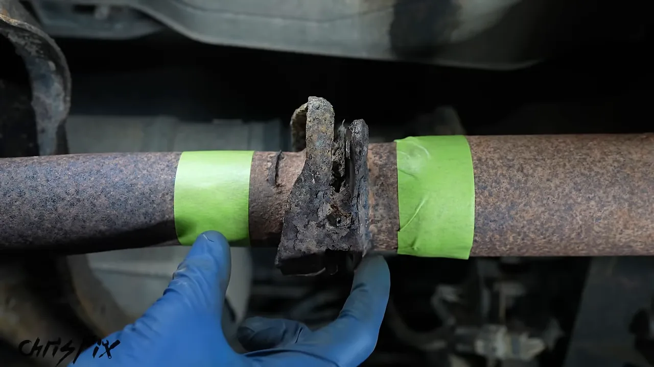 Green tape marking cut locations on both sides of a rusted exhaust flange