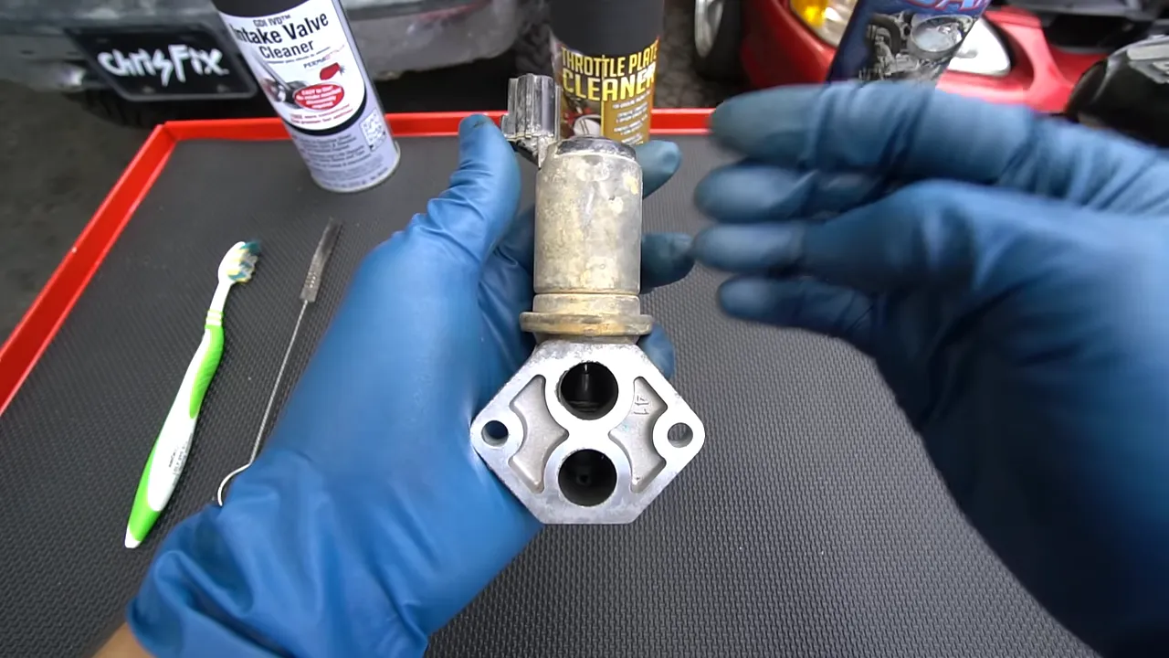 Idle air control valve held vertically with its cylindrical motor above the two air passages