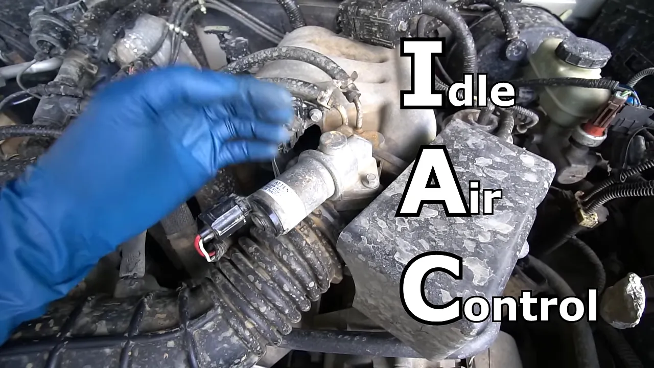 Gloved hand beside the pickup's idle air control valve with Idle Air Control text on screen