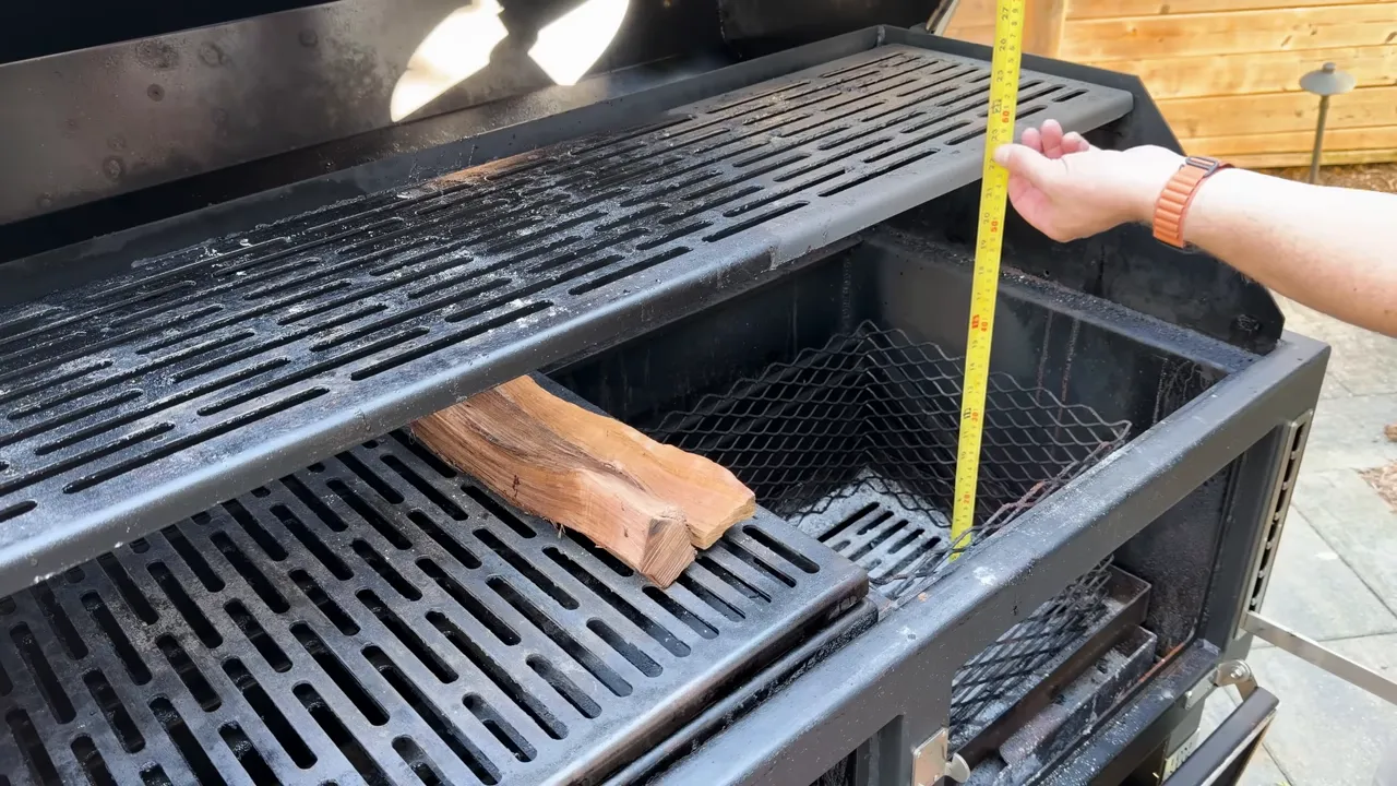 Tape measure held between the lowered charcoal basket and upper cooking rack of the open grill