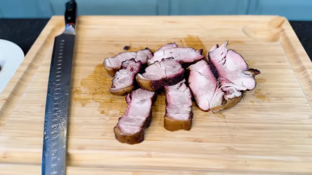 Sliced pork steak with browned edges and pink interior on a wooden cutting board
