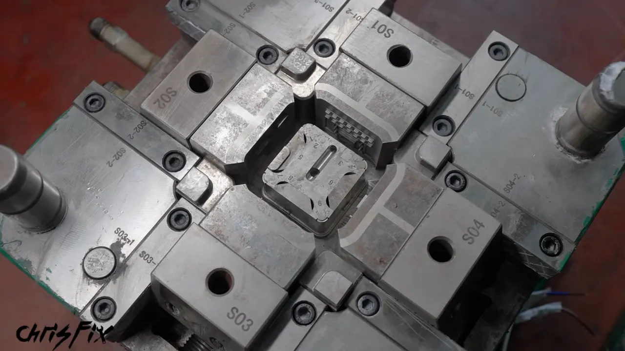 Close-up of the metal injection mold with a square cavity and surrounding tooling