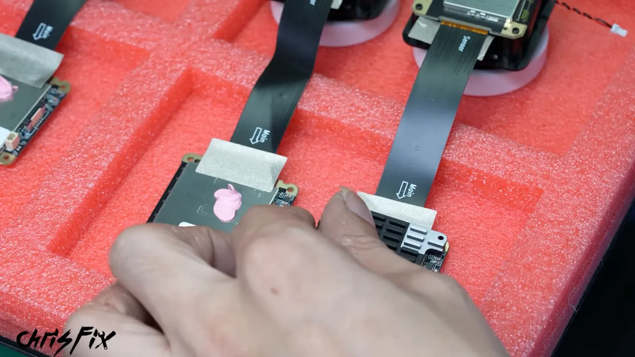 Dash camera circuit boards on a red tray with thermal paste and a black finned heat sink
