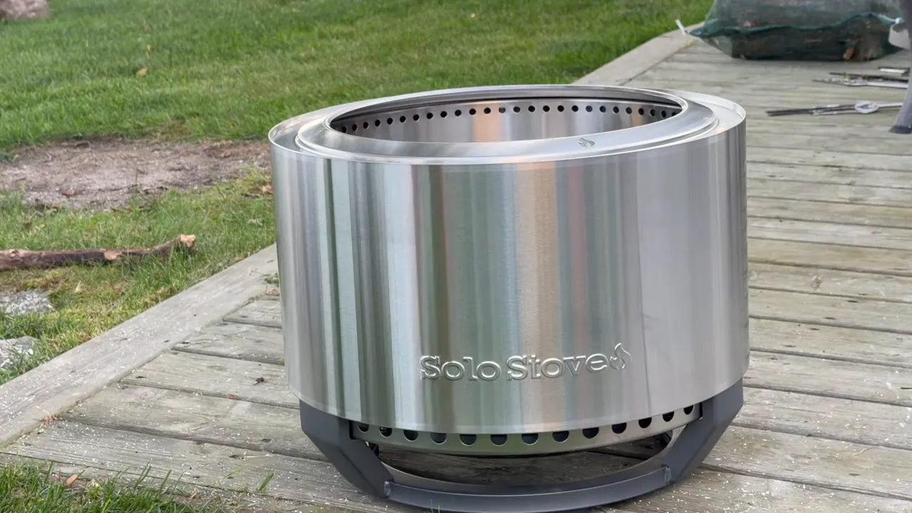 Stainless steel Solo Stove Summit with an integrated dark stand on a wooden deck
