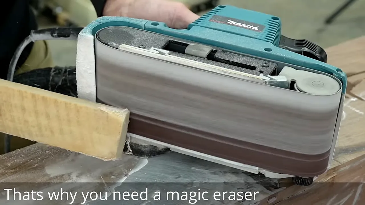 Abrasive cleaning stick held against the belt of a handheld belt sander