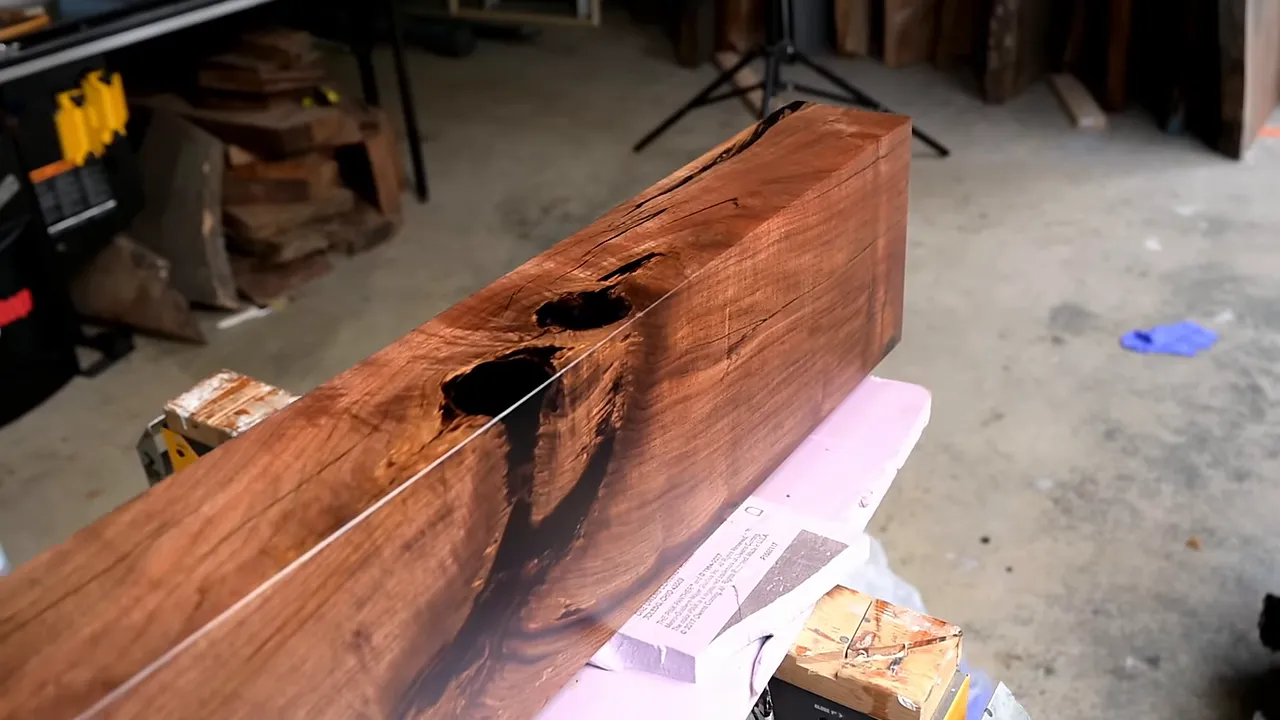 Finished walnut mantel with rich brown grain and large black-filled cracks resting on supports