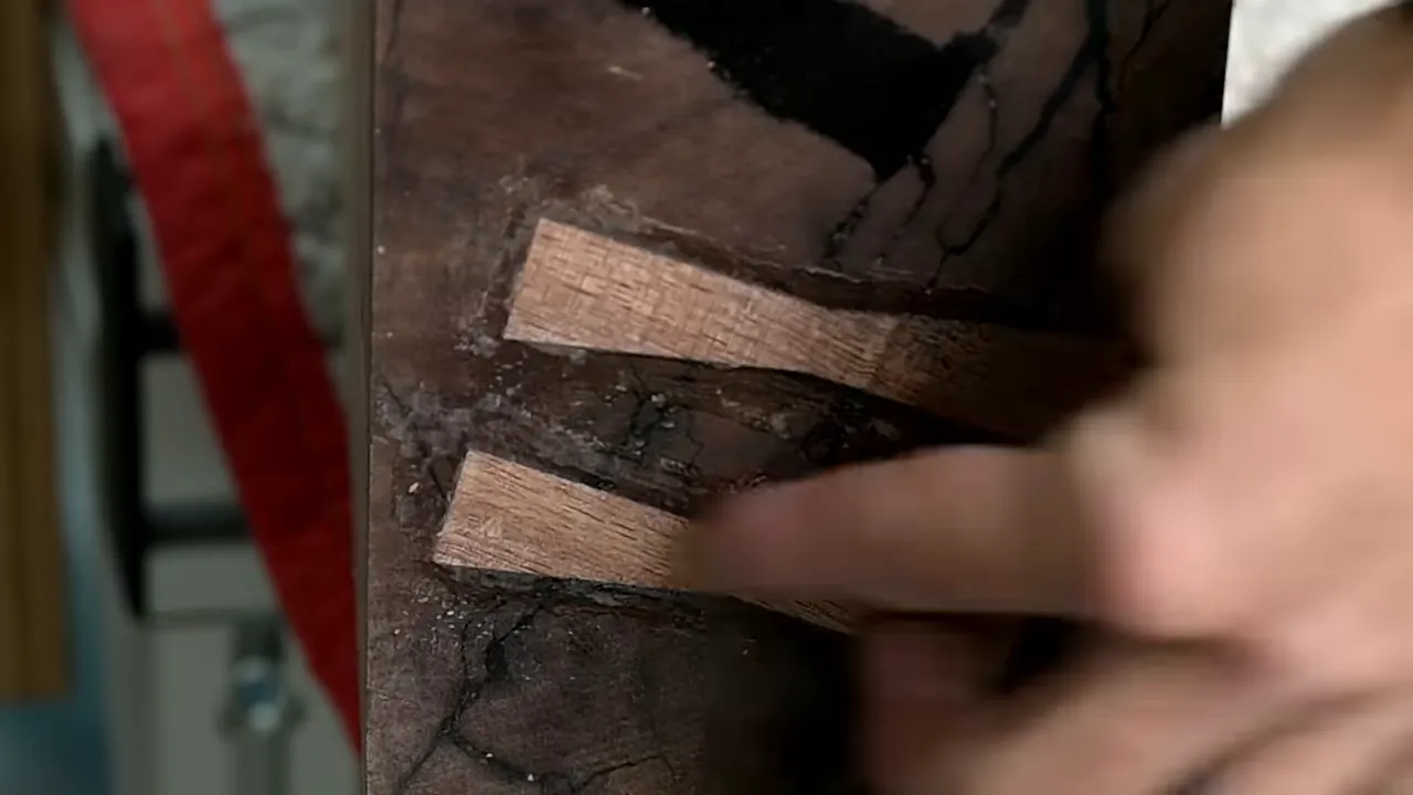 Two wooden bow tie inlays across dark cracks on the end of the walnut mantel