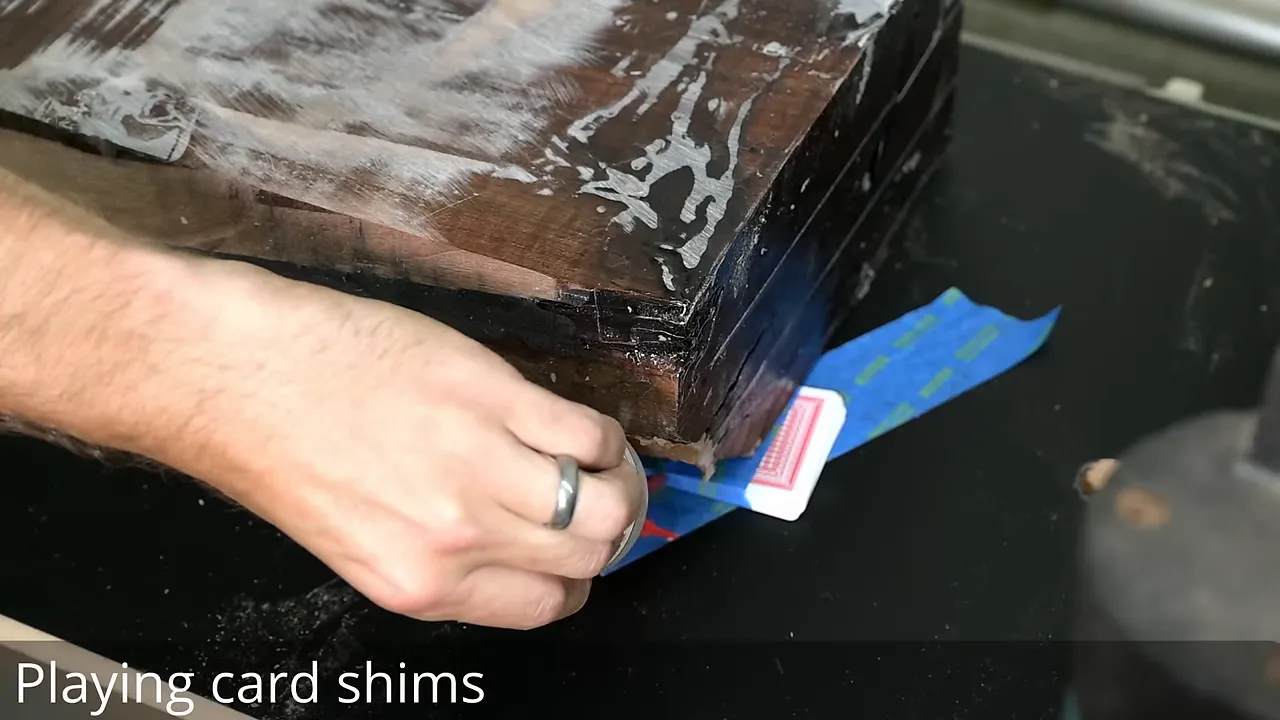 Playing cards used as shims beneath the walnut beam on a black planer sled