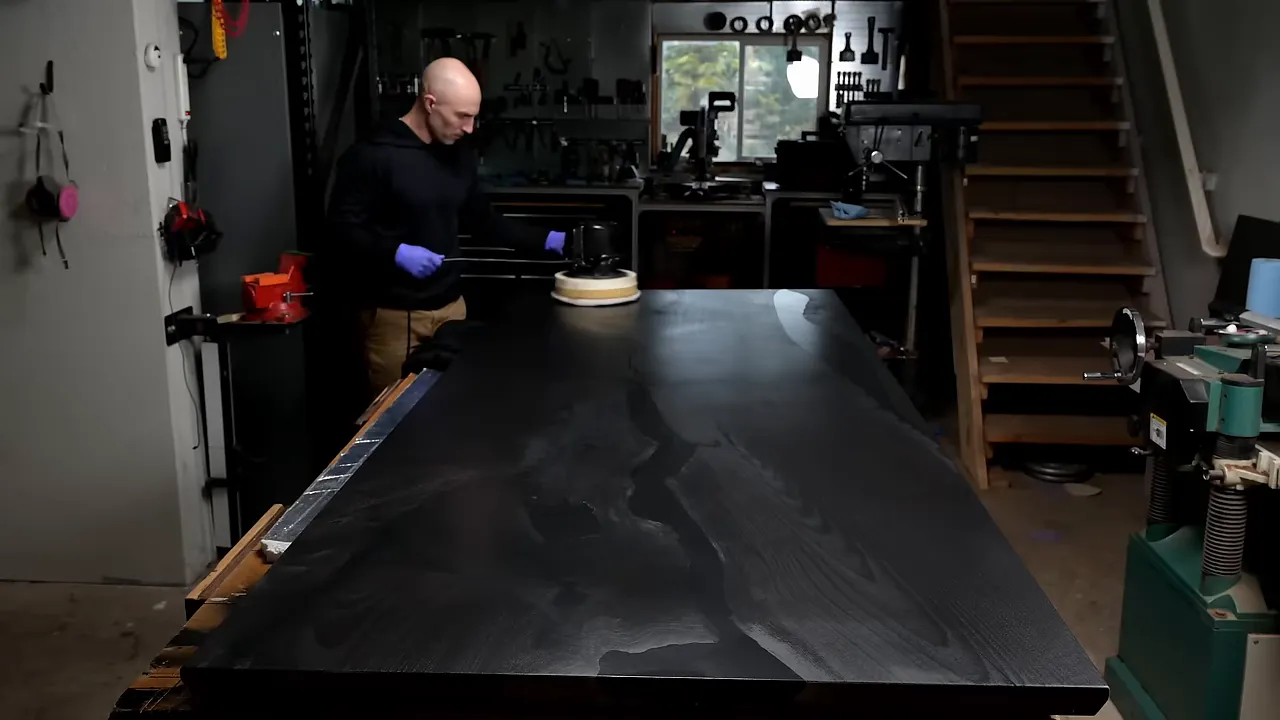 Large walnut tabletop covered with dark finish during application