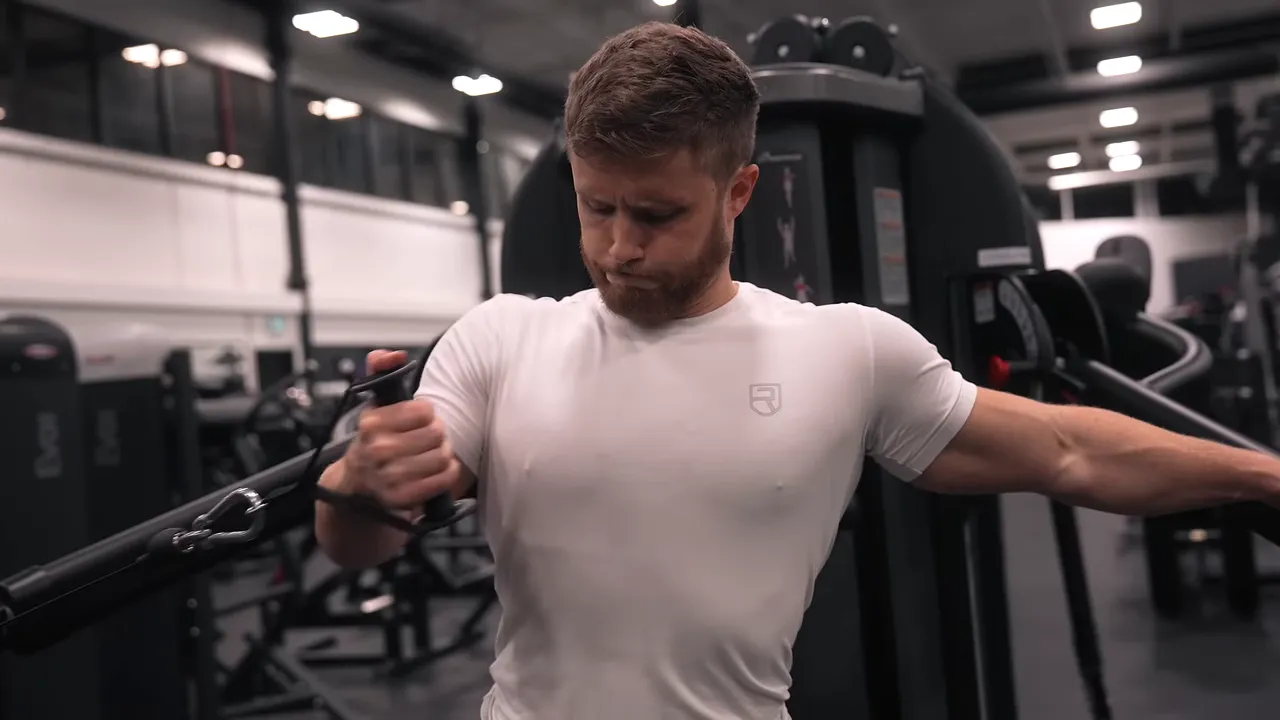 Lifter holding a cable handle across his chest with the working arm past the midline