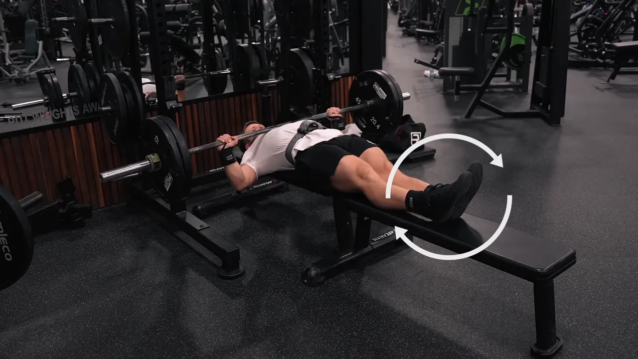 Lifter bench pressing with legs extended and feet supported on a second bench