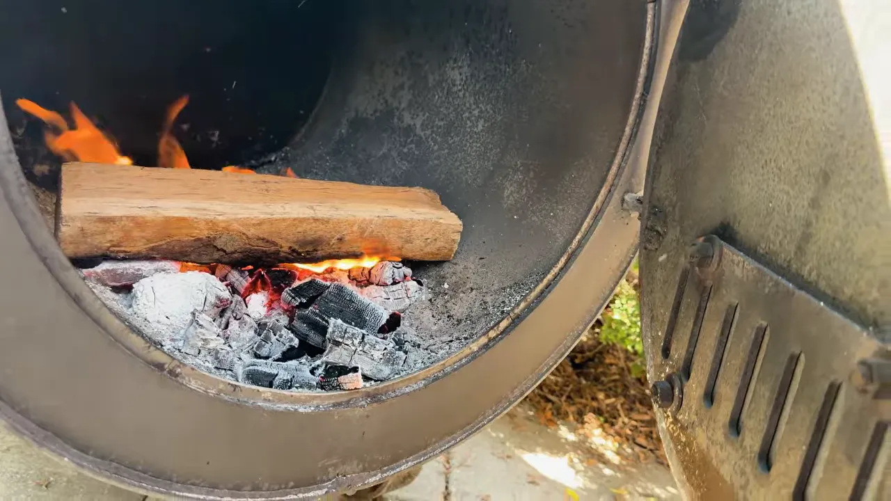 A single wood split burning above a bed of coals inside the G2 firebox