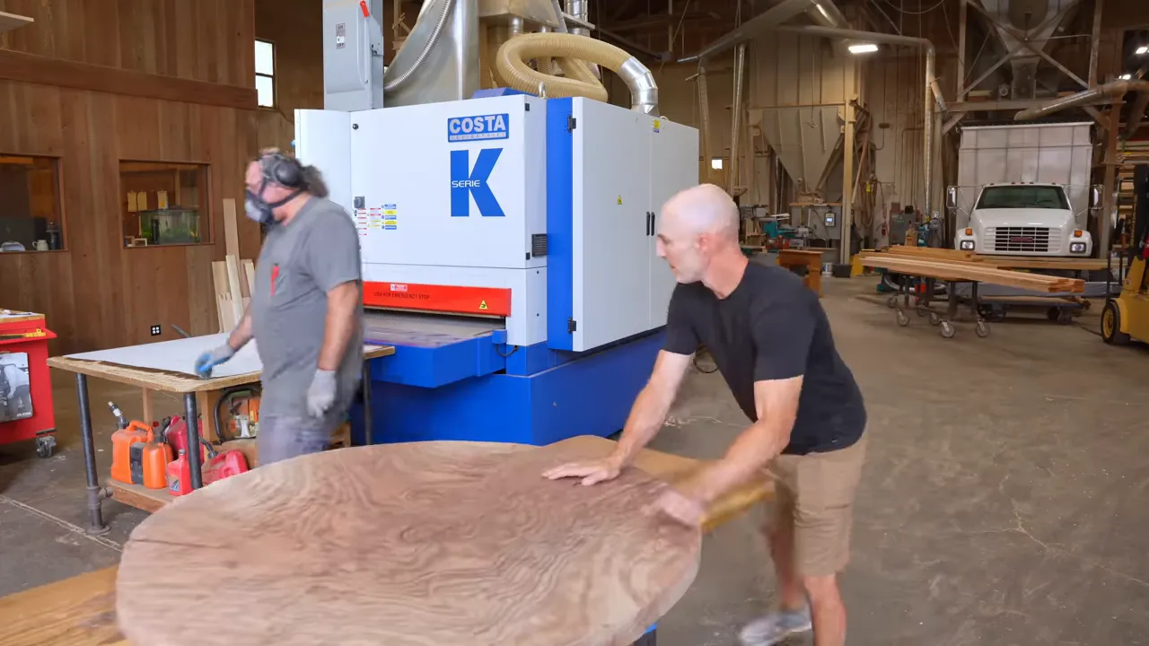 Rough round walnut tabletop with swirling grain resting on a work surface