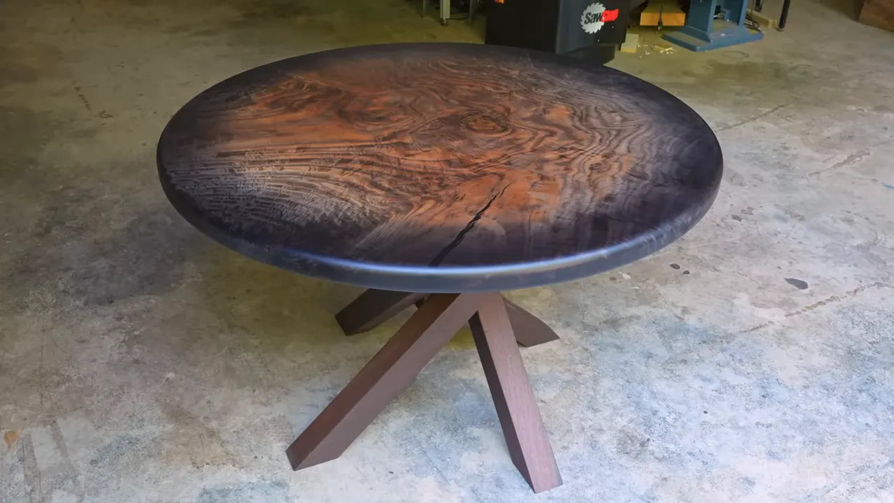 Completed round sunburst walnut table with a walnut spider base on a concrete floor