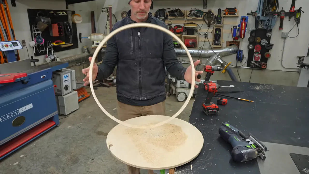 Plywood ring held above a circular plywood panel in the workshop