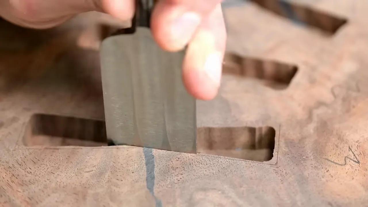 Chisel refining a bow tie recess that crosses a dark crack in walnut