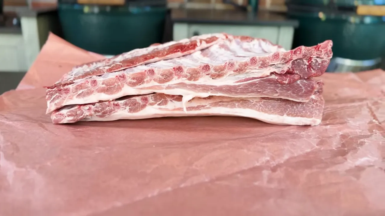 Thick raw pork ribs with attached belly resting on butcher paper