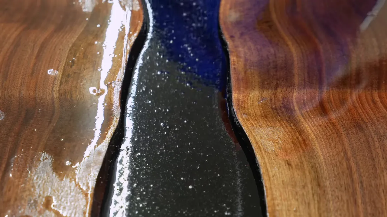 Black epoxy filling the gap between two wood slabs inside a white form