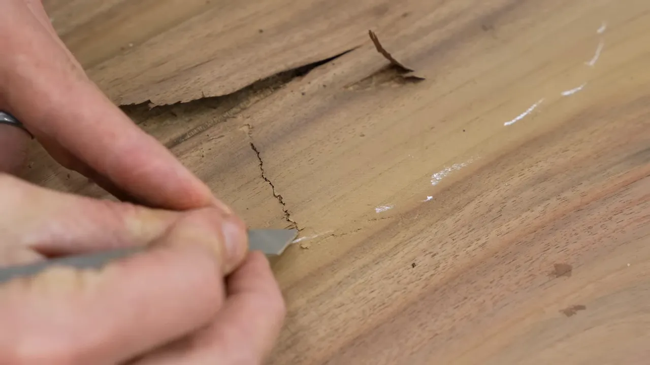 Hands opening a thin section of wood along a crack in the tabletop
