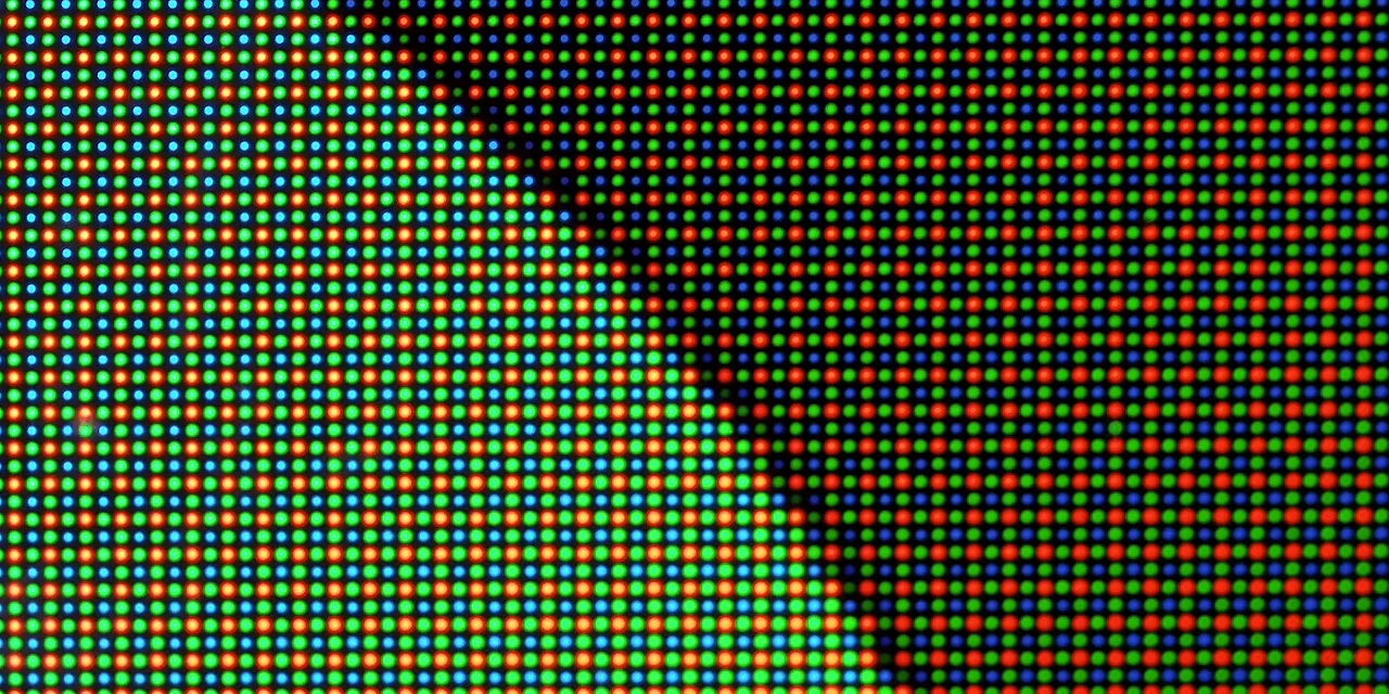 Microscope close-up of a dense illuminated red, green, and blue display pixel pattern
