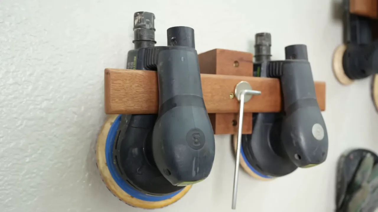 Two sanders hanging from wooden wall brackets with an Allen key on a round magnet