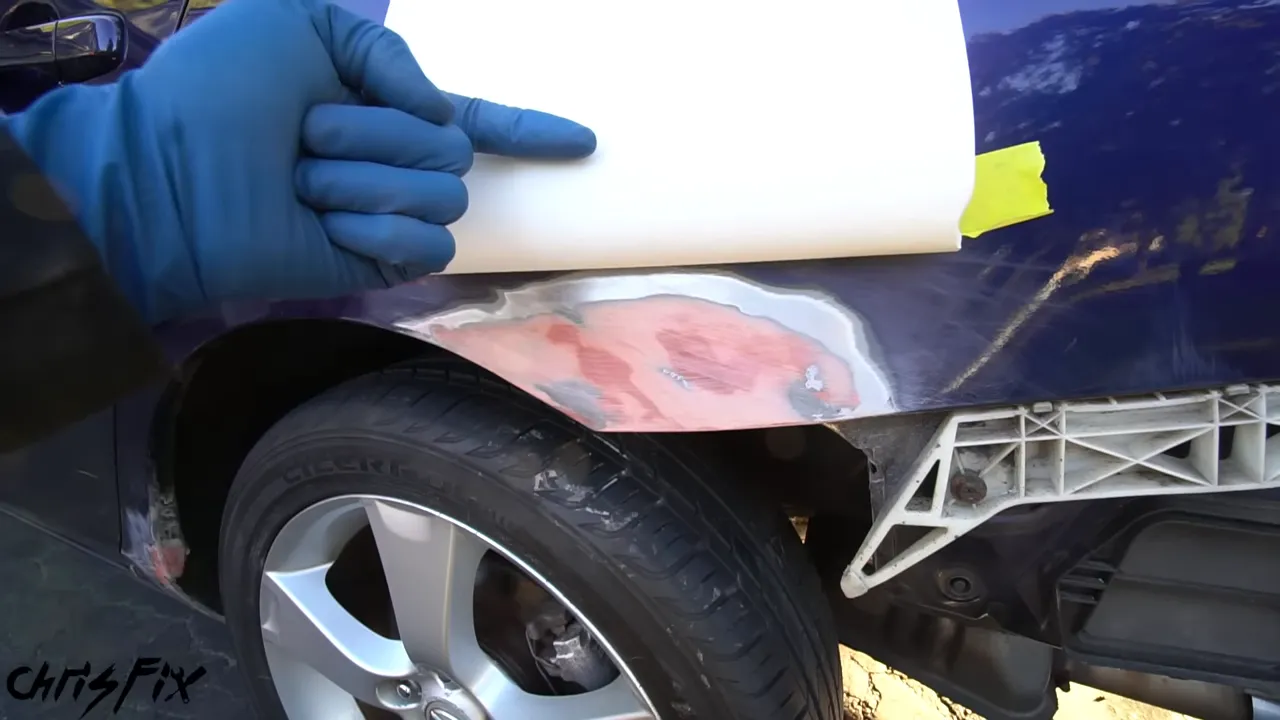 White masking paper folded into a curved edge above the sanded body repair