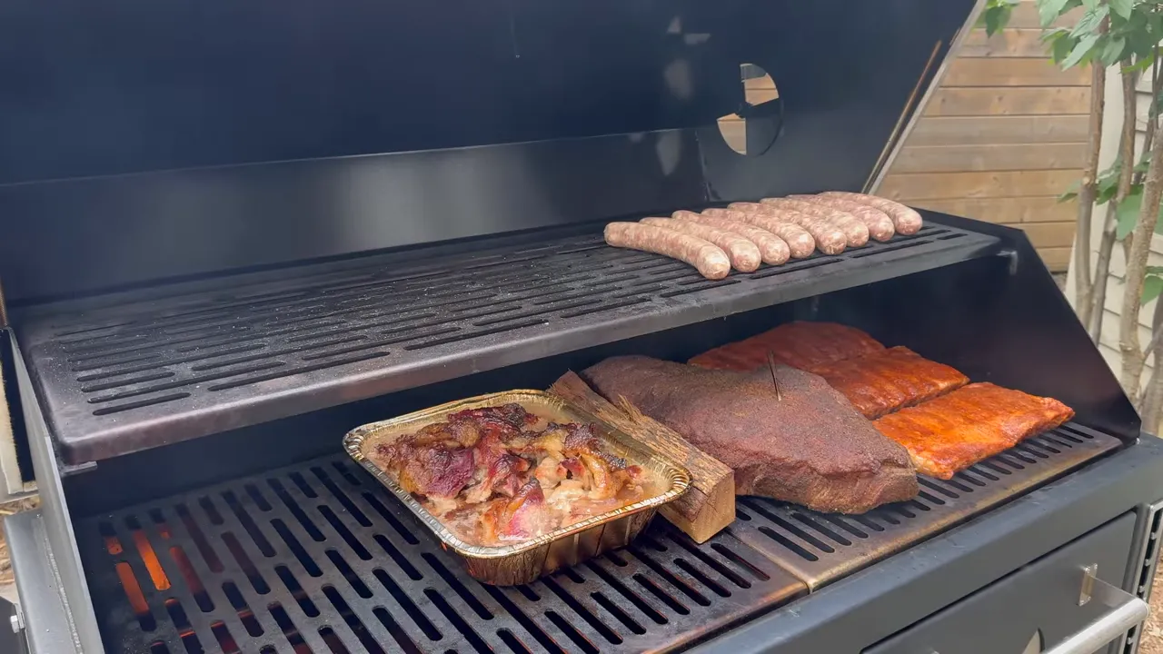 Open LSG grill with sausages on the upper rack and brisket, ribs, and a foil pan below