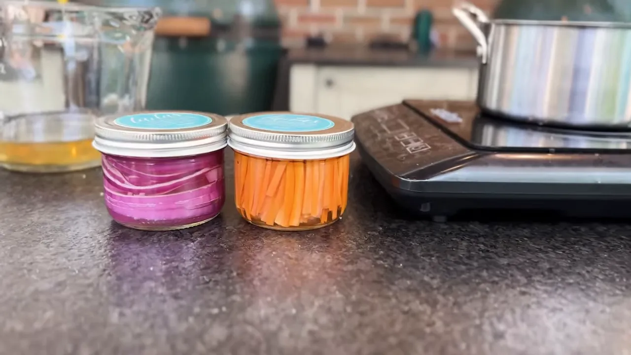 Small jars of pink pickled onion rings and orange carrot matchsticks beside a saucepan
