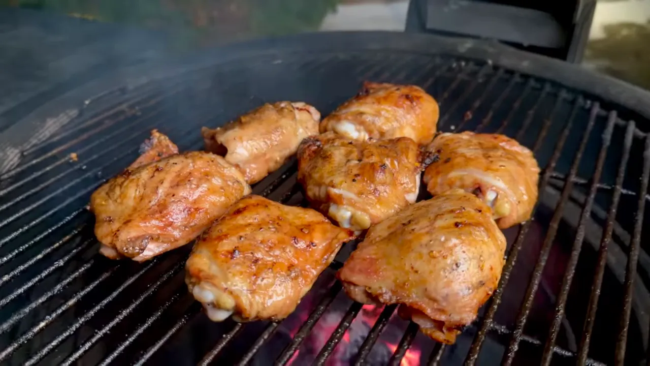 Browned chicken thighs cooking on black grill grates over glowing charcoal