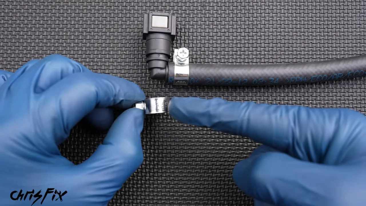 Fuel-injection hose clamp held beside a hose connected to a plastic elbow fitting