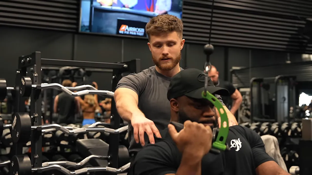 Quinton holds a single-arm pulldown handle while Jeff gestures beside his arm