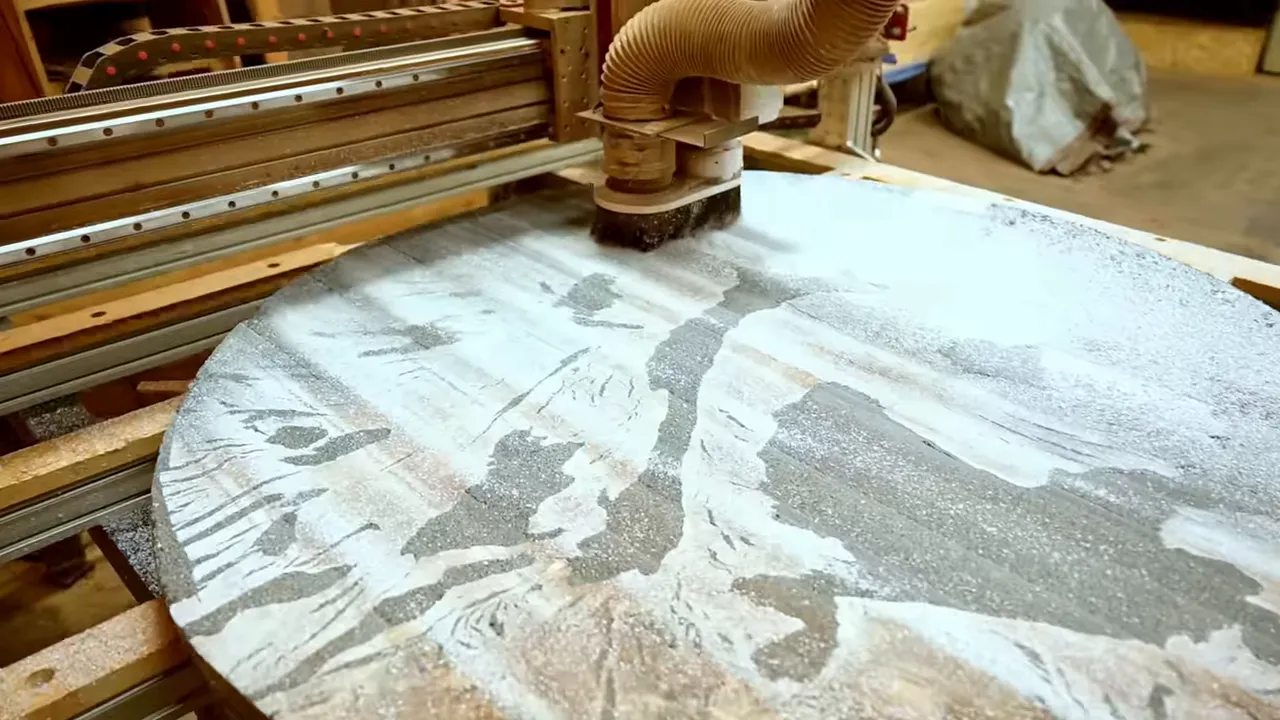 CNC surfacing head over a round tabletop with pale machining tracks across the surface