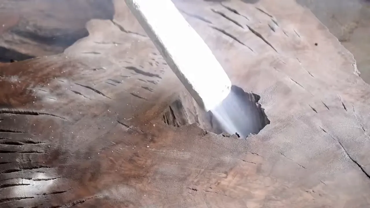 Close view of a blasting nozzle directed into cracks in the walnut slab