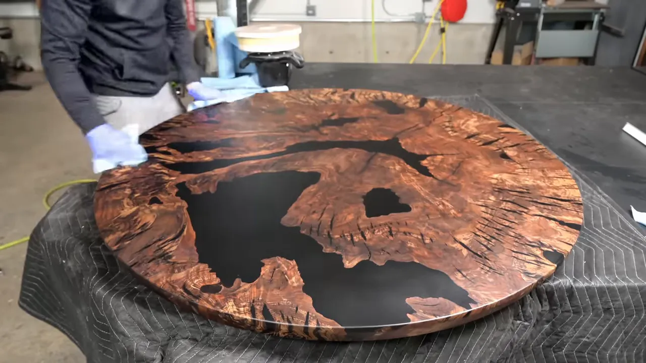 Finished round walnut tabletop with dark epoxy filling large branching voids